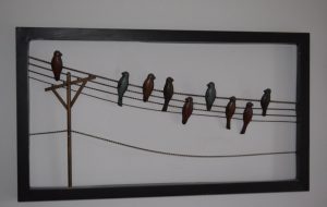 An all-metal wall art featuring birds on a telegraph wires with a pole.