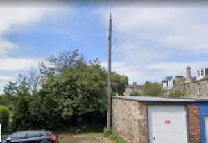 A pole with a long thin finial on top adjacent some garages in a part of Edinburgh