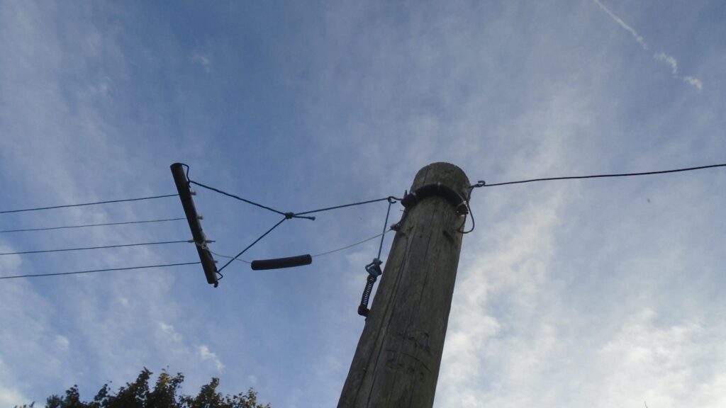 A pole with a quadruple array of SW antennae slung from it. Blue sky background